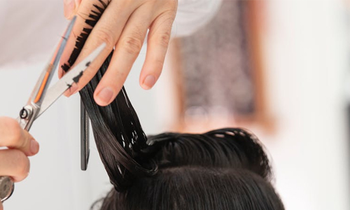 person getting her long black hair cut