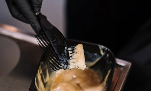 person dipping a brush into wax