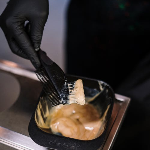 person dipping a brush into wax